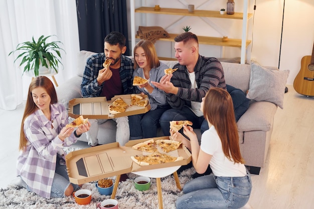 Comendo uma deliciosa pizza Grupo de amigos fazem festa dentro de casa juntos