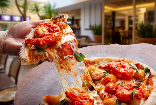 Comendo uma fatia de pizza à mão, pizza de camarão com tomate cereja