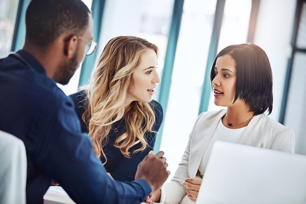 Comentando algunas ideas de sus colegas Captura recortada de tres empresarios trabajando juntos en la oficina