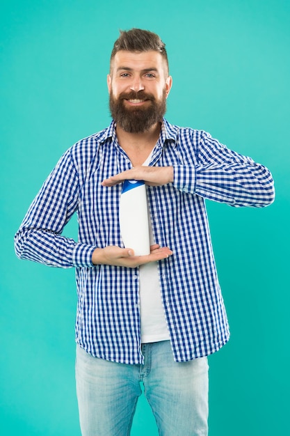 Comenzando un nuevo día con una sonrisa brutal hipster sostenga una botella de champú Hombre barbudo con cabello saludable Cosmético para baño de spa barba cuidado del cabello aseo belleza masculina autohigiene buenos días mi elección