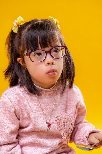 Comer bocadillos. Niña atenta con ojos marrones con síndrome de down y peinado oscuro funky