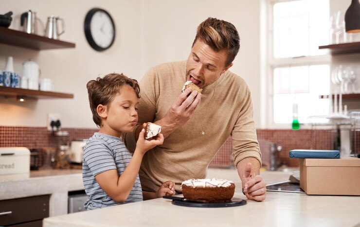 Foto comer bolo e pai com o filho na cozinha em casa com doce para o pequeno-almoço ou lanche feliz ligação e pai desfrutando de sobremesa com o menino filho para a refeição da manhã ou desejo juntos em casa