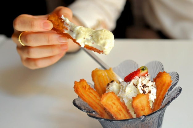 Comer churros españoles bañados en helado de vainilla con los dedos