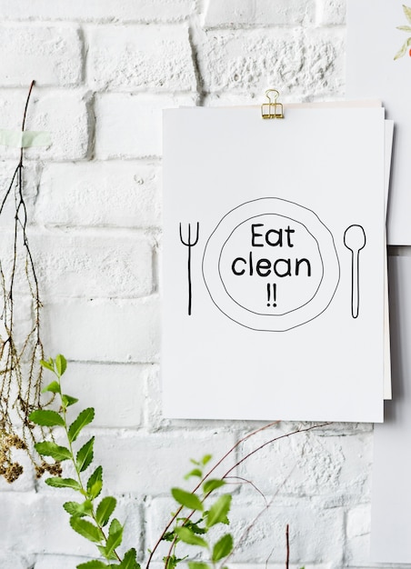 Comer comida limpia inspirada en un póster de papel en una pared blanca.