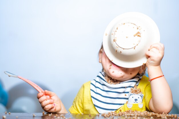 Foto comer engraçado do bebê. bebezinho jantando e fazendo bagunça.