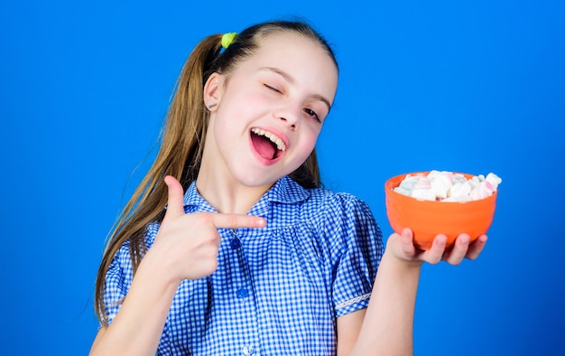 Comer malvavisco. Dulcería. feliz niño le encanta comer dulces y golosinas. La pequeña niña come malvaviscos. Alimentos saludables y cuidado dental. Dieta y calorías. Concepto goloso. comiendo.