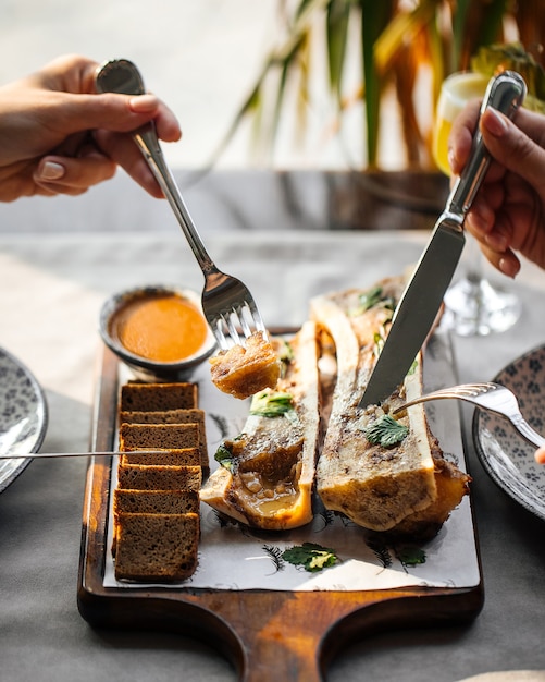 Comer médula ósea gourmet con salsa y pan de centeno con cubiertos