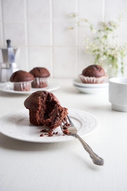 Comer muffins con un tenedor Muffins en vasos de papel en un plato sobre fondo blanco.