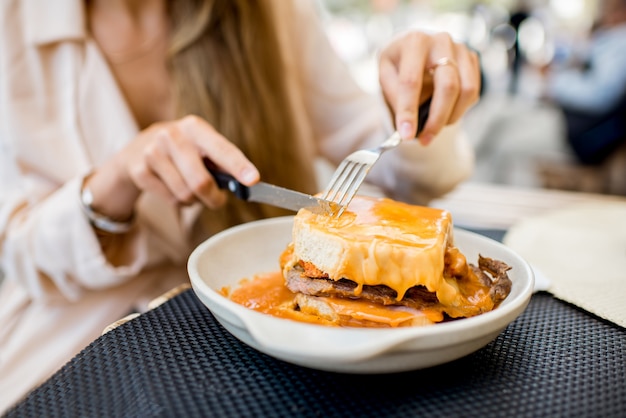 Comer sándwich de carne tradicional portuguesa con salsa de tomate llamado francesinha en el restaurante de la ciudad de Oporto