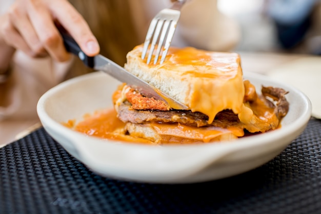 Comer sándwich de carne tradicional portuguesa con salsa de tomate llamado francesinha en el restaurante de la ciudad de Oporto