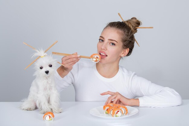 Comer sushi japonês conjunto Beleza jovem e cachorro comendo sushi com pauzinhos isolados no branco Rolo de sushi com pauzinhos Comida japonesa saudável