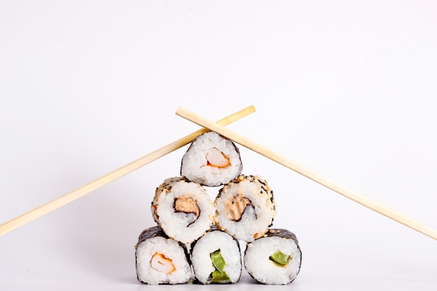 Comer sushi con palillos. Sushi roll comida japonesa en restaurante aislado sobre fondo blanco.