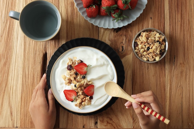 Comer yogur griego y granola para el desayuno