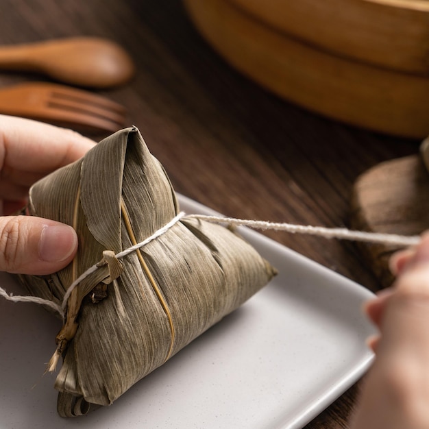 Comer zongzi Dragon Boat Festival Rice dumpling joven asiática comiendo comida tradicional china en una mesa de madera en casa celebración cerrar