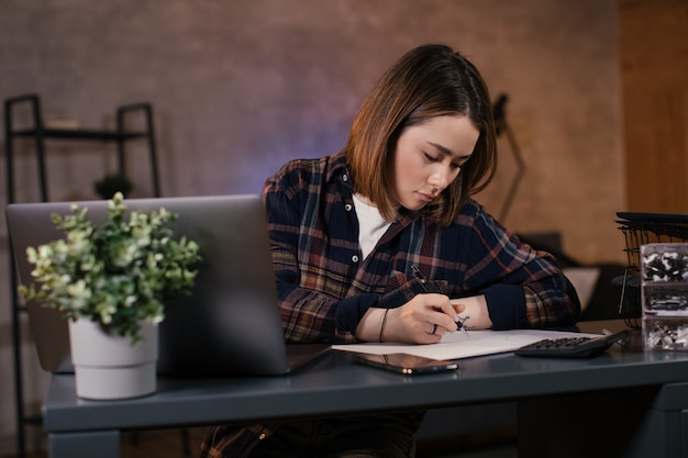 Foto comerciante de chica asiática trabajando en una computadora portátil en casa