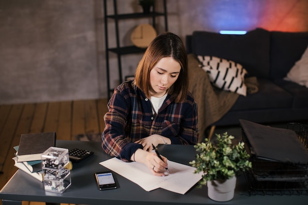 Comerciante de chicas asiáticas trabajando en casa en la mesa, estudiando el gráfico