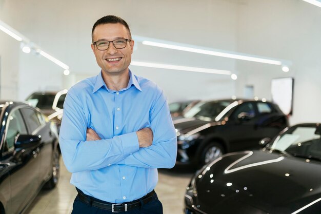 Foto comerciante de carros de pé na sua loja.