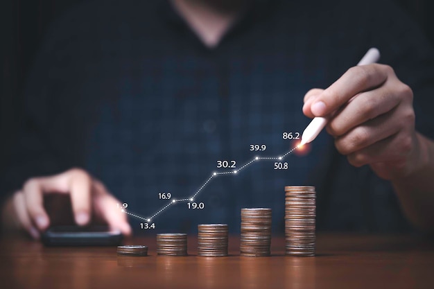 Comerciante escrevendo gráfico crescente no empilhamento de moedas para crescimento do lucro do investimento e conceito de economia