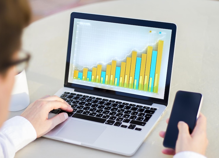 Foto comerciante está mirando gráficos financieros en el monitor de la computadora