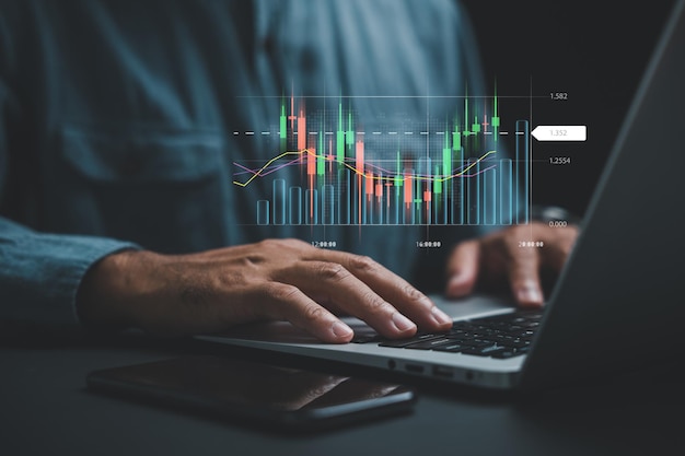 Un comerciante o inversor en casa que ejecuta operaciones y analiza el mercado de valores en una pantalla de computadora portátil que muestra gráficos de precios técnicos gráficos de velas e indicadores comerciales