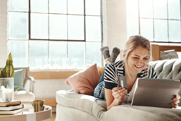 Comércio eletrônico de tablet e pagamento de menina com cartão de crédito no sofá para dados bancários no cartão Mulher relaxada no sofá de casa com sorriso feliz e satisfeito para transação de compra de compras on-line