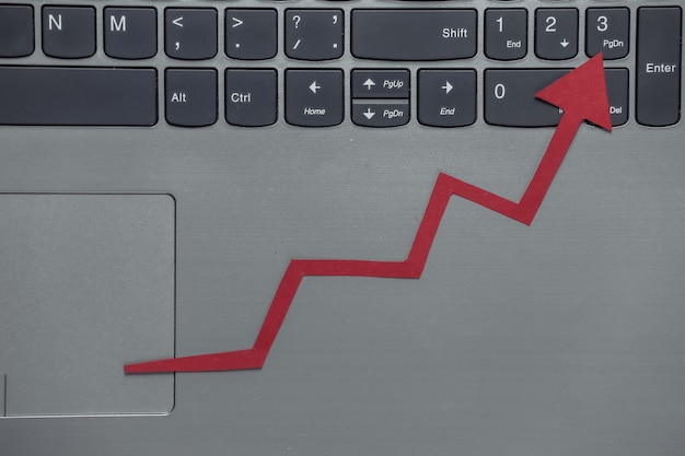 Comercio en línea, comercio. Teclado de computadora portátil con flecha roja de crecimiento. Gráfico de flecha subiendo.