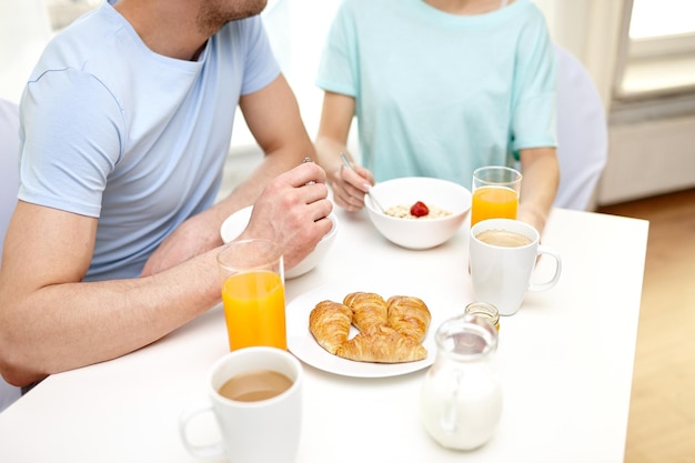 Comida, alimentação, pessoas e conceito de comida saudável - close-up de casal tomando café da manhã em casa