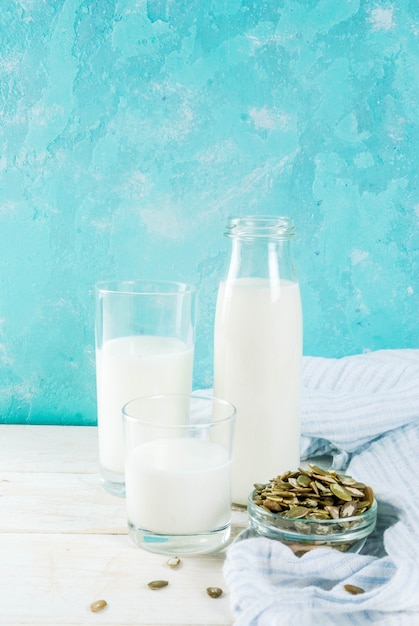 Comida alternativa vegana, semillas de calabaza, leche no láctea sobre fondo azul claro, espacio de copia