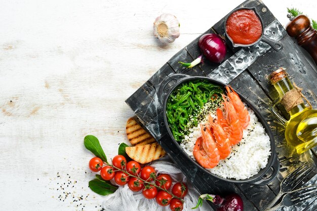 Comida asiática Camarones de arroz y ensalada Chuka en un tazón negro Estilo rústico Vista superior Espacio libre para su texto