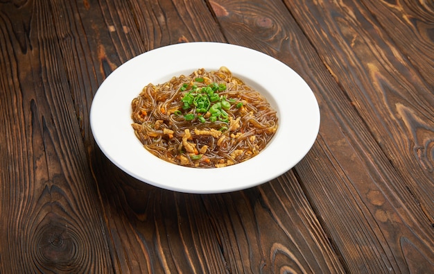 Comida asiática. Fideos fritos de cristal con carne y verduras. Fideos chinos de arroz de cristal fritos con carne y tomates. Fideos de celofán funchoza coreanos