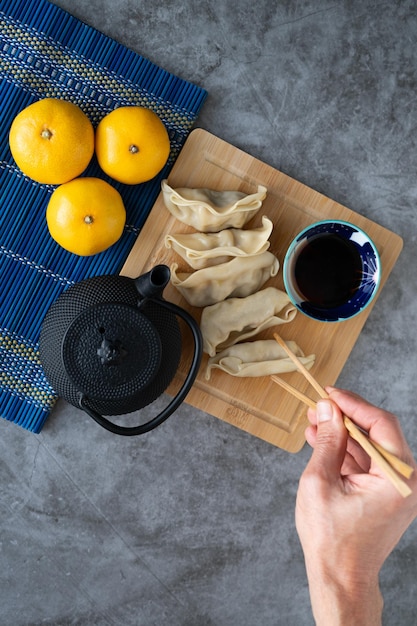 Comida asiática Mano recogiendo comida con palillos Dim sum con salsa de soja en tablero de bambú Copiar espacio Vista superior