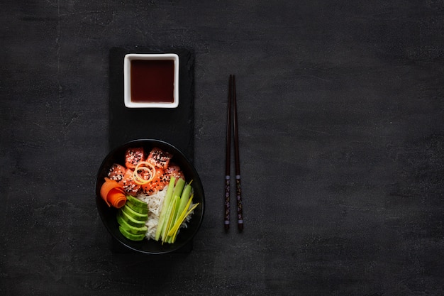 Comida asiática na moda, tigela de sushi poke com pepino, salmão, cenoura, abacate, sementes de gergelim