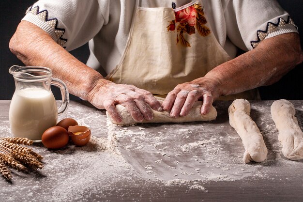 Comida auténtica israelí. anciana, abuela manos mezclando polvo para hacer pan delicioso. Pan jalá crudo