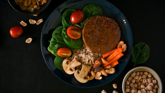 Comida a base de plantas con carne vegana, arroz integral, espinaca, tomate, champiñón, zanahoria, nueces y garbanzos