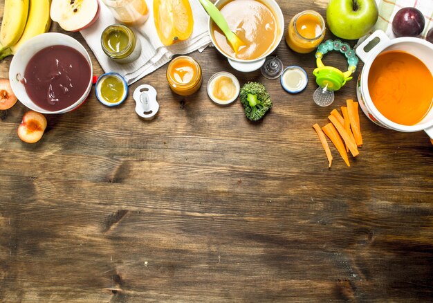 Foto comida para bebé. variedad de purés de frutas y verduras para bebés. sobre una mesa de madera.