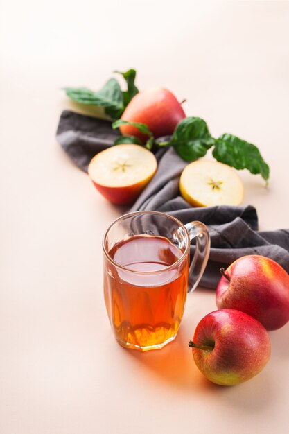 Comida y bebida, concepto de cosecha otoño otoño. Jugo de manzana orgánico fresco en una taza con frutas maduras sobre fondo de coral rosa de moda