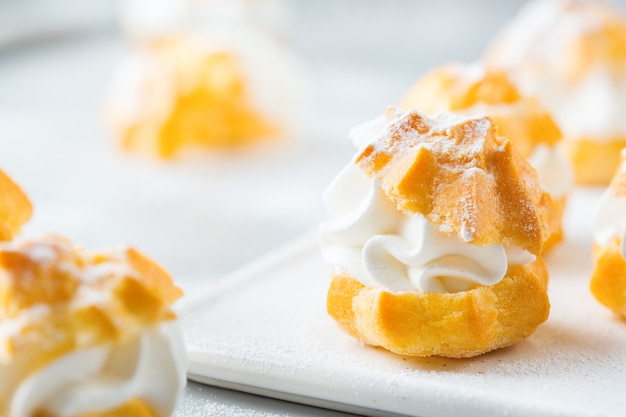 Comida y bebida, concepto de vacaciones. Profiteroles caseros dulces deliciosos con crema en una mesa de cocina moderna