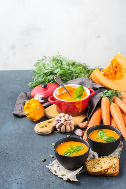 Comida y bebida naturaleza muerta concepto de dieta y nutrición Temporada otoño otoño sopa de zanahoria calabaza naranja asada con ingredientes en una mesa de madera rústica Espacio de copia acogedor fondo de cocina