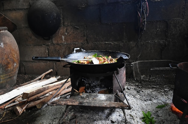 comida caliente en la sartén vieja en la antigua estufa en el campo en el norte de Tailandia