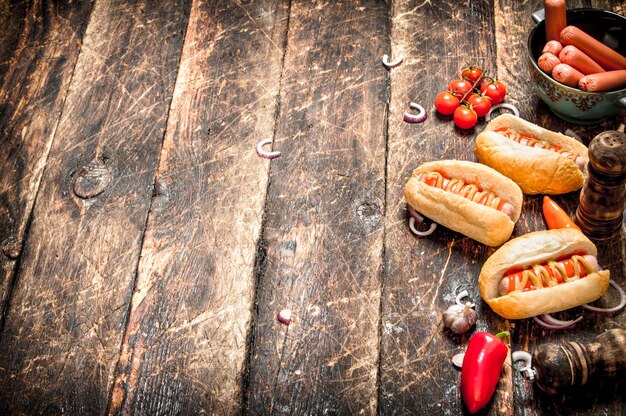 Comida de la calle. Perritos calientes frescos con pimientos, cebollas y tomates en la mesa de madera.