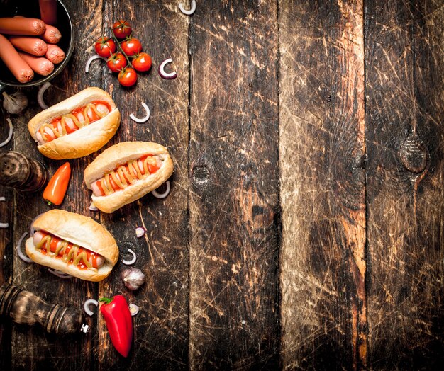 Comida de la calle. Perritos calientes frescos con pimientos, cebollas y tomates en la mesa de madera.