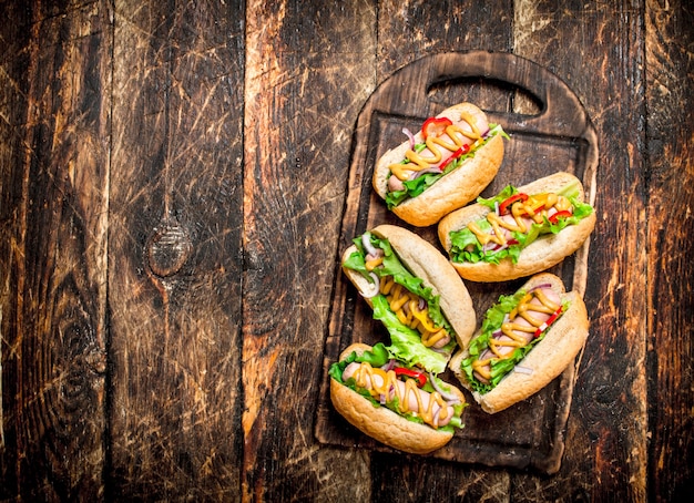 Comida de la calle. Perritos calientes con hierbas, verduras y mostaza caliente en mesa de madera.