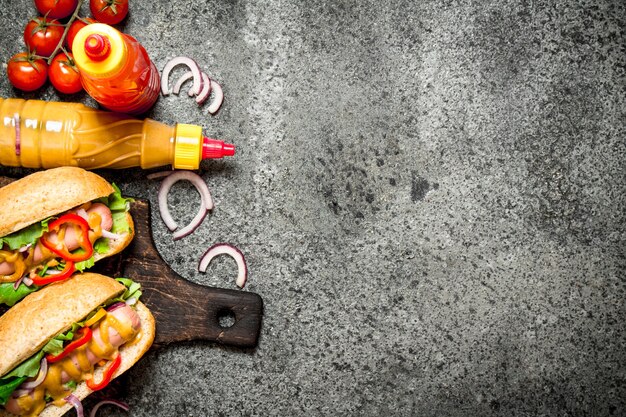 Comida de la calle. Perritos calientes con verduras y hierbas de mesa rústica.