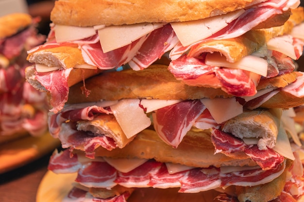 comida callejera española de primer plano pan de baguette recién horneado con jamón ibérico curado en rodajas bocadillo