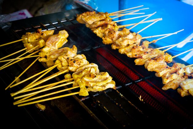 Comida callejera tailandesa BBQ, satay de cerdo asado a la parrilla en la estufa o cerdo asado al estilo tailandés en el mercado