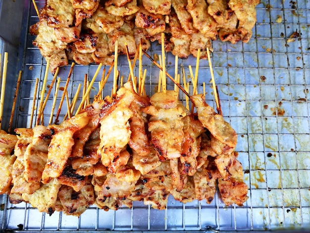 Comida callejera tailandesa a la parrilla palo de cerdo en el mercado de pulgas