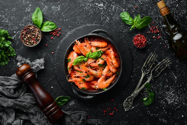 Foto comida camarão cozido em molho de tomate com manjericão em um prato de pedra preta vista superior espaço livre para o seu texto