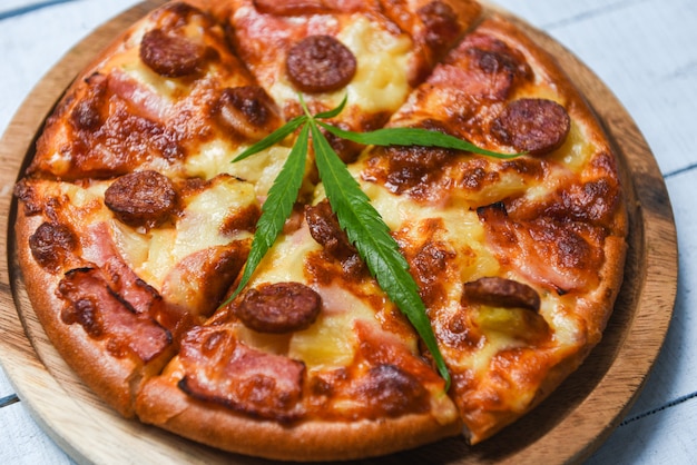 Comida de cannabis con pizza en bandeja de madera y chile albahaca hoja vista superior