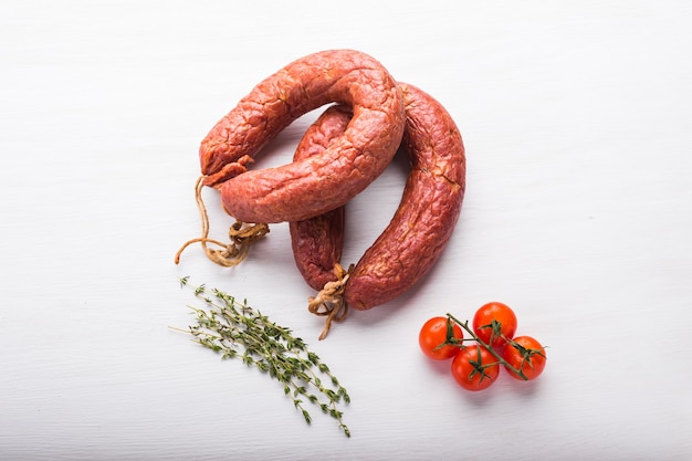 Comida, carne y concepto delicioso: salchichas hechas con carne de caballo con tomates en la mesa