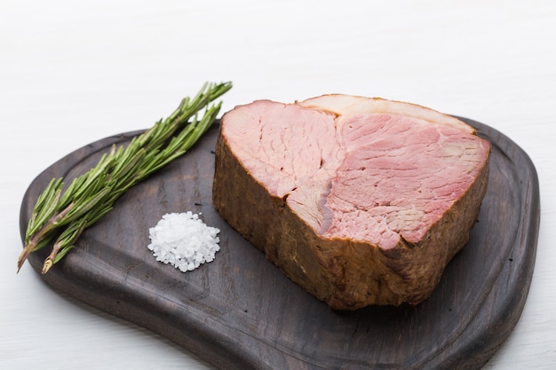 Comida, carne e conceito delicioso - close-up de carne de cavalo com sal em uma placa de corte.